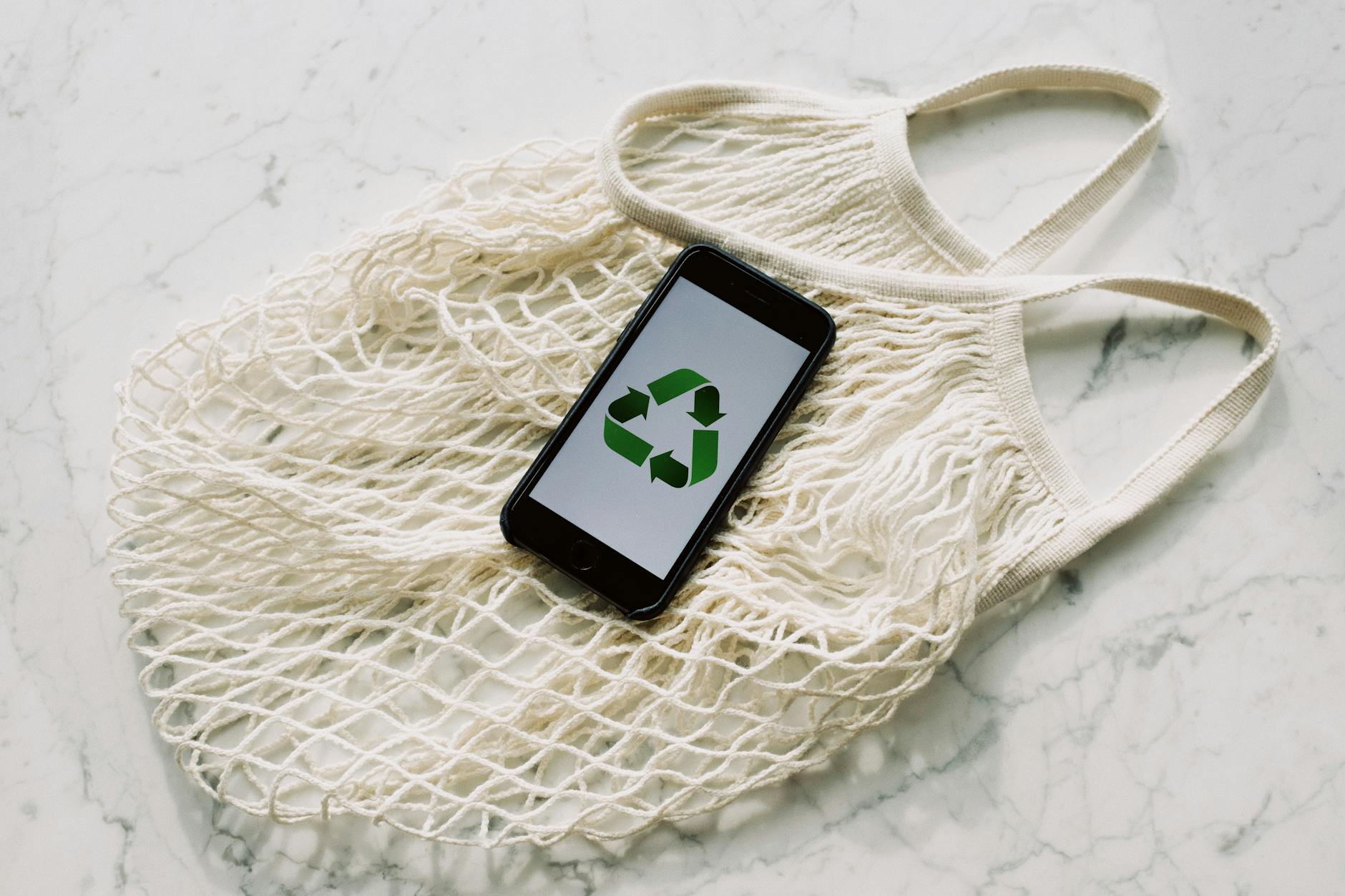 mobile phone with green recycling sign and mesh bag